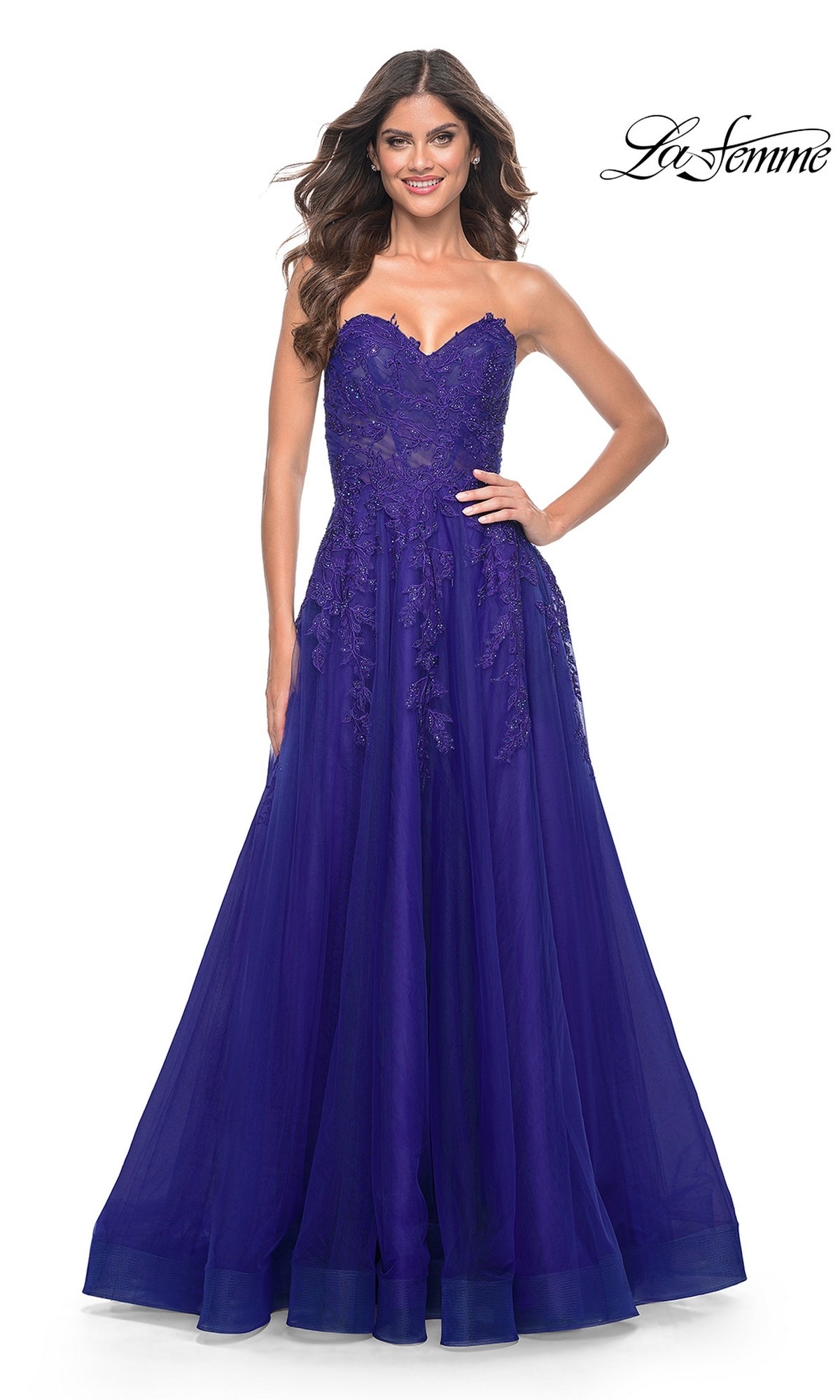 A woman stands smiling against a white background wearing the La Femme Lace-Up Long Sweetheart Prom Dress 32304 in deep blue, featuring a strapless neckline, lace embellishments, and an elegant A-line silhouette.